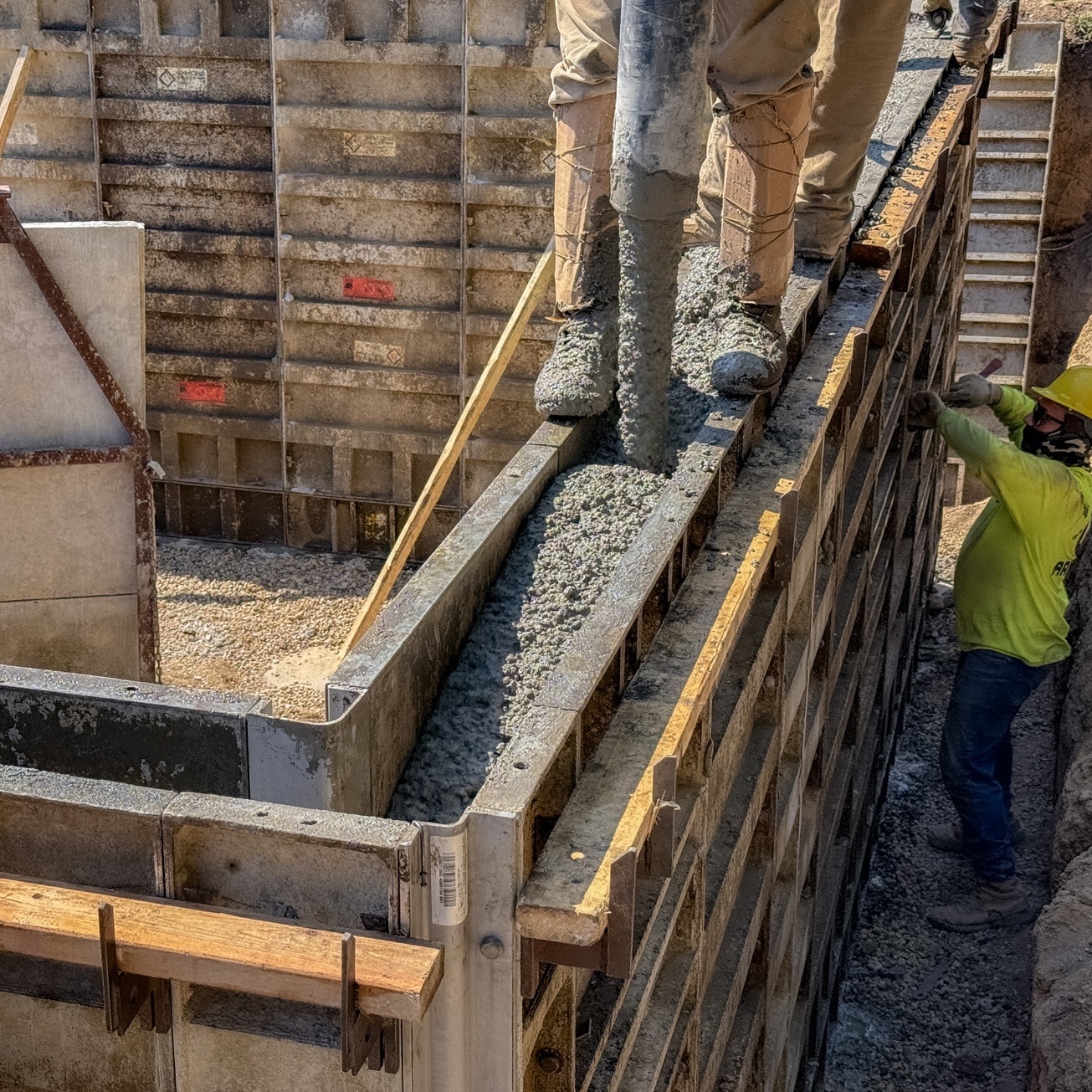 Crew pouring concrete into foundation forms